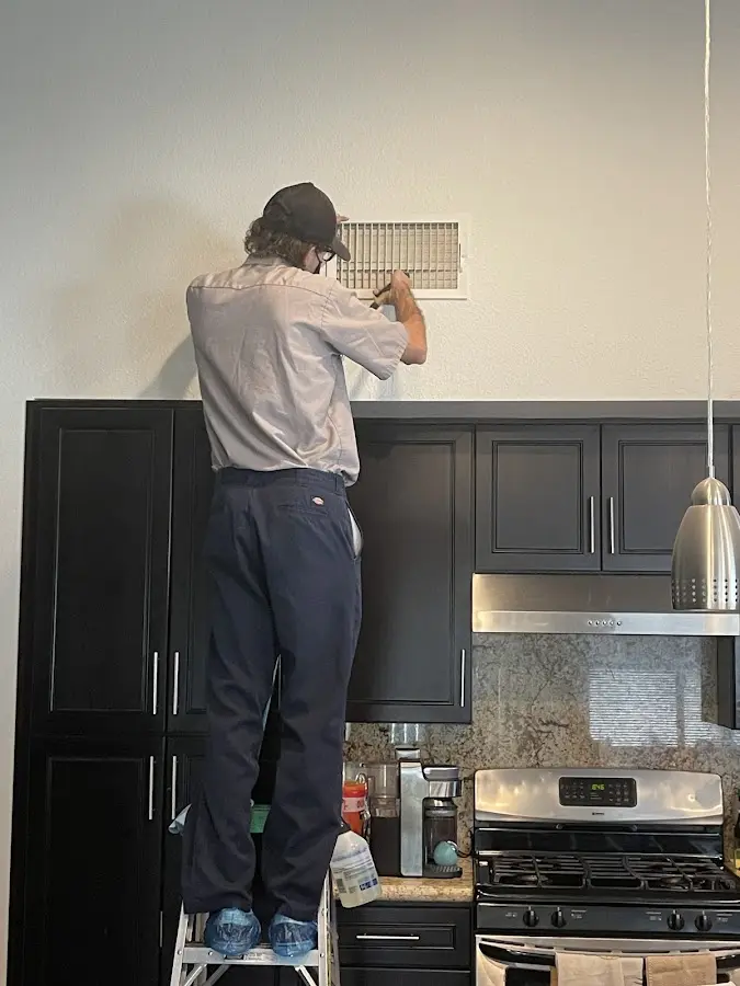 Technician inspecting an air vent during HVAC service in Uwchlan